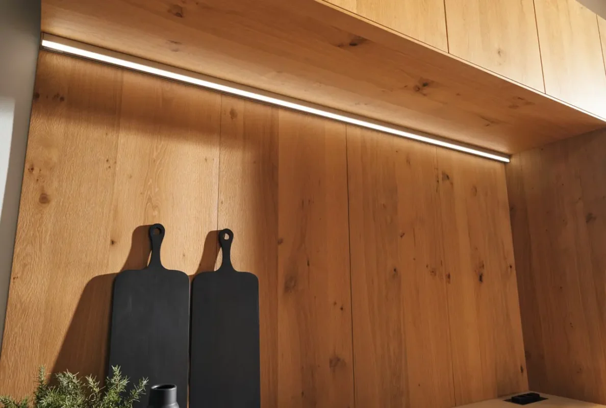 Kuhinja Legno sa prirodnim drvenim panelima i elegantnim ambijentalnim osvetljenjem ispod visećih elemenata