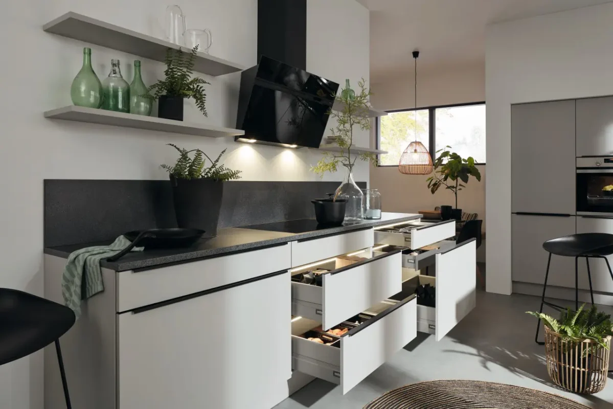 Nolte kuhinja Feel sa otvorenim fiokama, modernim crnim aspiratorom, crnom radnom površinom i prirodnim detaljima u svetlom enterijeru